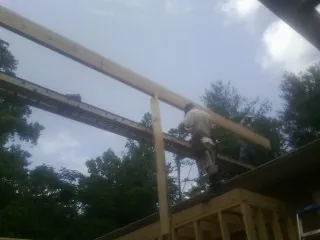 Carpenter setting a ridge beam over a new addition frame — Ice Dam Removal by Roofing Brothers in Polson