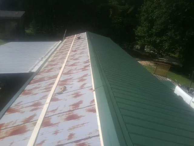 Old rusted panels beside newly installed green metal roofing — Wind Damage Roof Repair by Roofing Brothers in Polson
