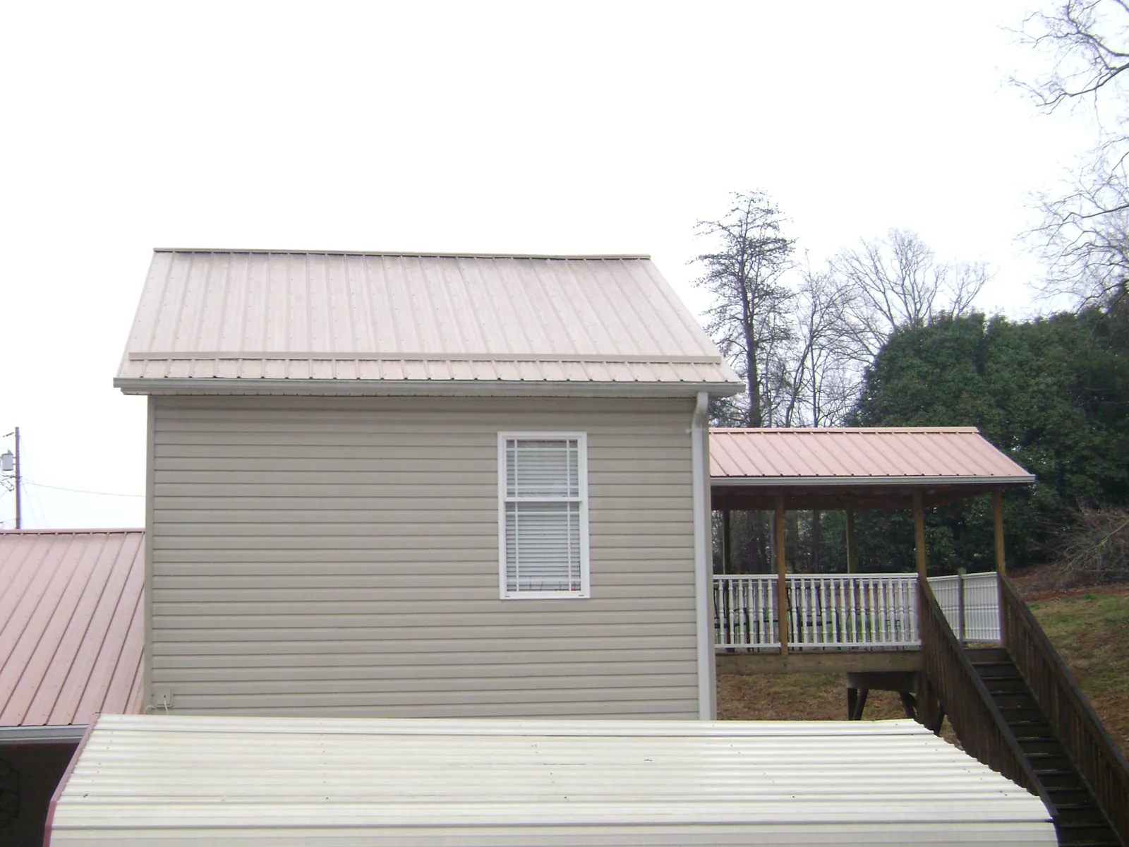 Tan metal roofs on a two story addition and attached porch, from a Roof Replacement job in Polson