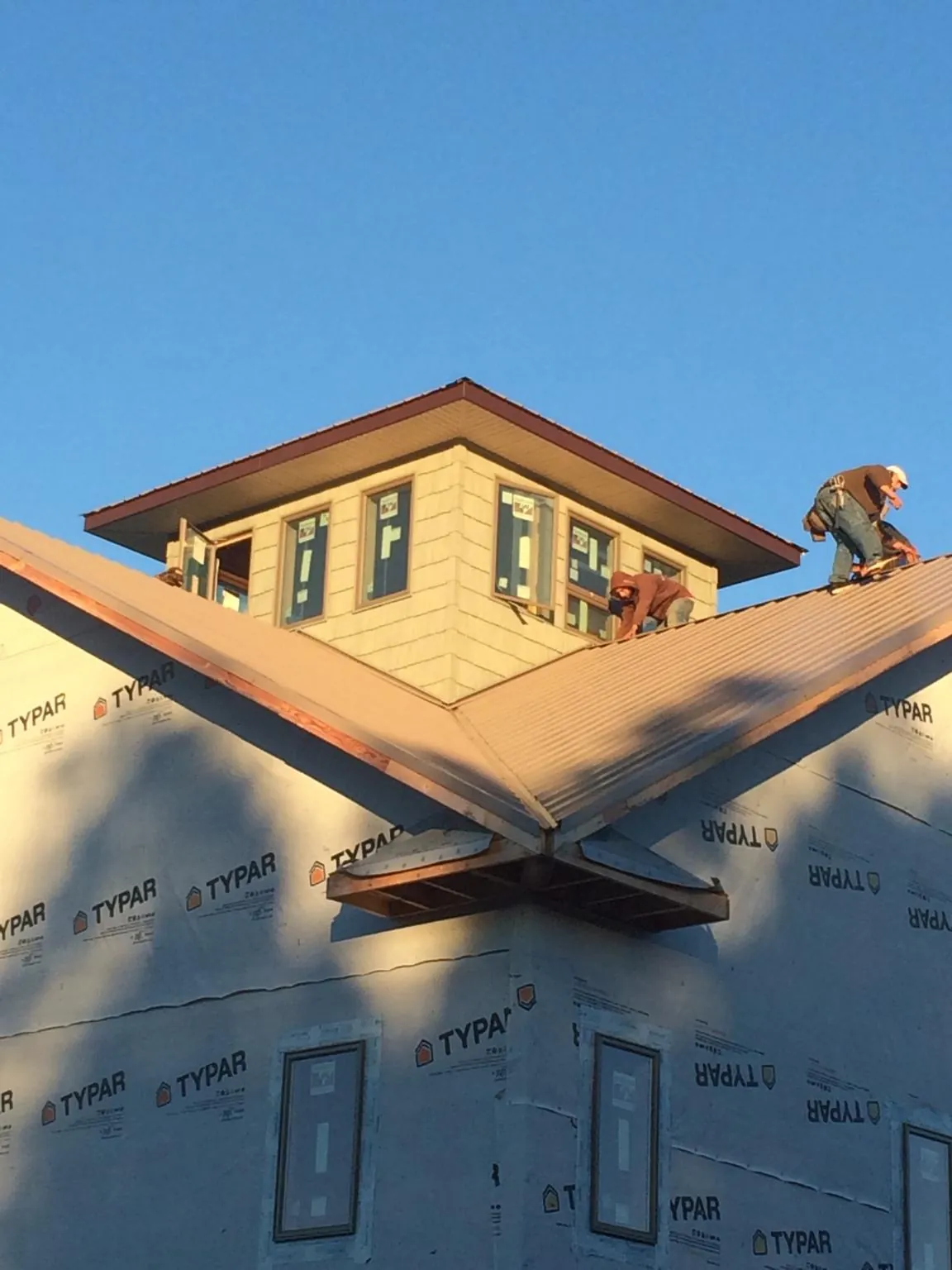 Roofers working around a rooftop cupola on a new metal roof at sunset — Roof Waterproofing in Polson by Roofing Brothers
